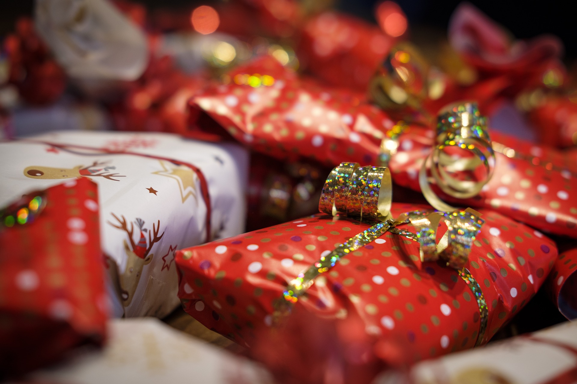 Auf folgenden Bild sind mehrere Rote eingepackte Geschenke zusehen, außerdem haben diese jeweils eine Goldene Glitzende Schleife. Das Bild dient als Hintergrund des Blog beitrages